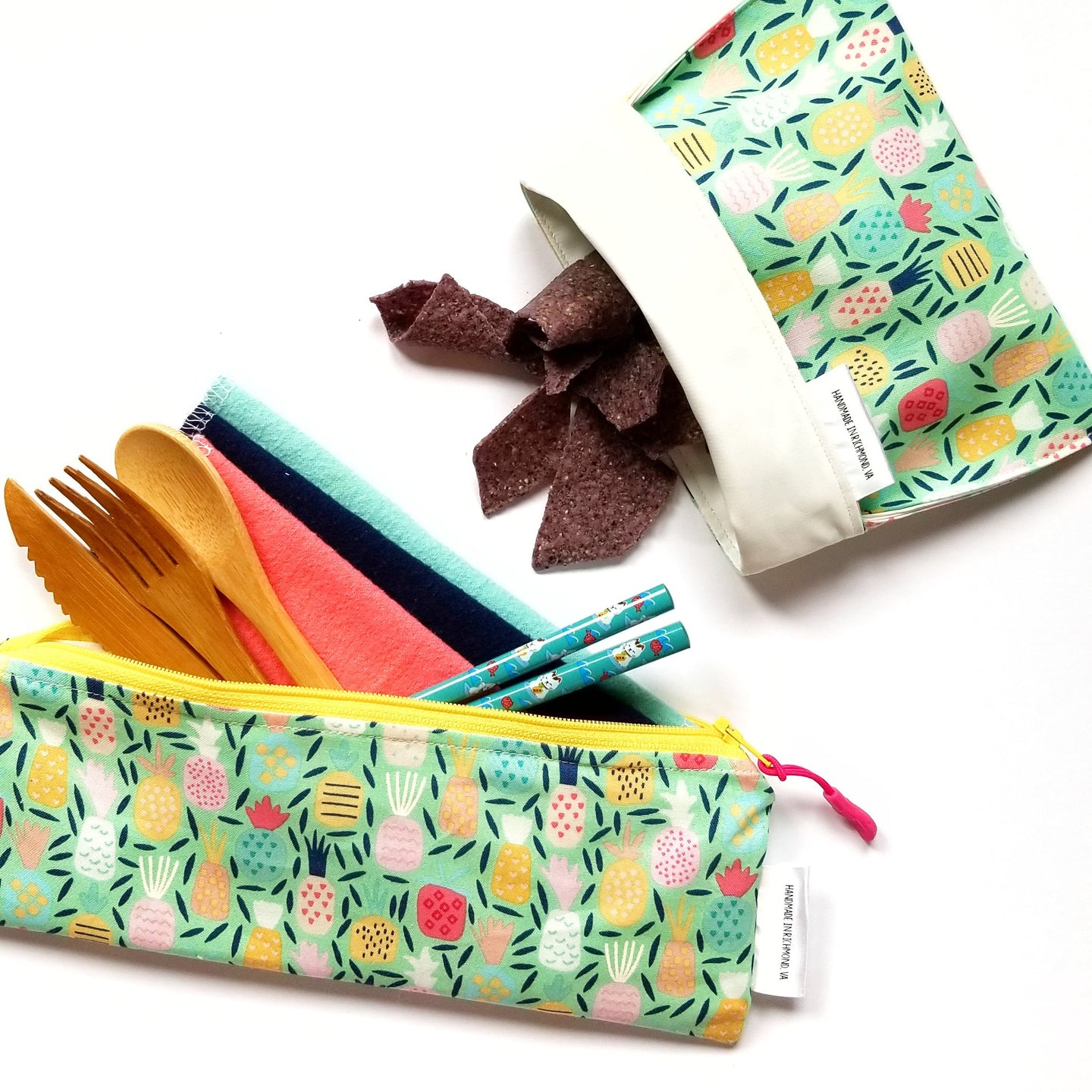 Cutlery pouch with cloth napkins, bamboo cutlery, and chopsticks, as well as a reusable snack bag with chips in it.